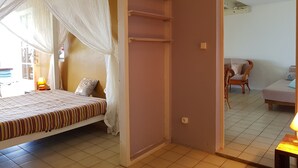 Un dormitorio con cama, mesita de noche, silla y una pequeña mesa con lámpara.