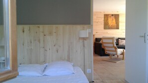 A bedroom with a wooden headboard, a bed with white linens, a chair, and a painting on the wall. - Promo end of August 25% 3 bedroom cottage of 85m2 with south facing terrace of 60m2  (Saint-Cyr-La-Roche)