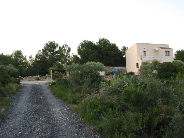 A gravel path leading to a building with a sign that reads "MELTEMI".