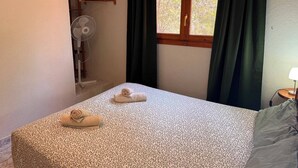 A bedroom with a bed, a fan, a window with curtains, and a wall-mounted towel rack. - Wonderful country house with private pool (El Perelló)