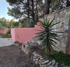 A landscaped area with a stone wall, a small rock garden, and a large agave plant. - Wonderful country house with private pool (El Perelló)