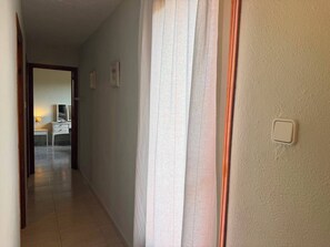 A hallway with a door leading to a room, a light switch on the wall, and a lamp on a table. - Wonderful country house with private pool (El Perelló)