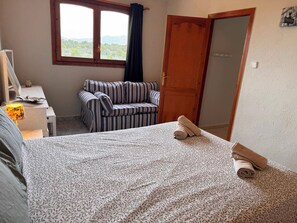 A room with a bed, a striped sofa, a desk with a lamp, and a view through a window. - Wonderful country house with private pool (El Perelló)