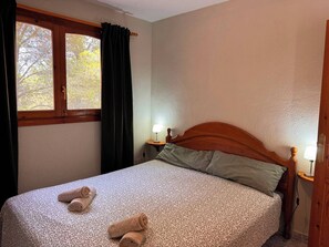 A single bed with a patterned bedspread, two rolled towels, a nightstand with a lamp, and a window with curtains. - Wonderful country house with private pool (El Perelló)
