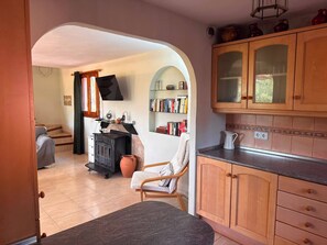 A cozy kitchen with wooden cabinets, a built-in bookshelf, and a rustic stove. - Wonderful country house with private pool (El Perelló)