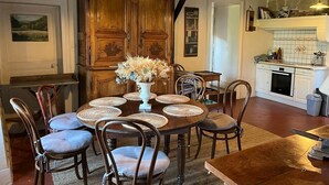 A dining area with a round table, chairs, and a wooden cabinet. - Adorable country house in the heart of a hamlet overlooking the valley (Authiou)