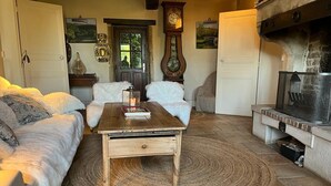 A cozy living room with a fireplace, a wooden coffee table, and a sofa. - Adorable country house in the heart of a hamlet overlooking the valley (Authiou)