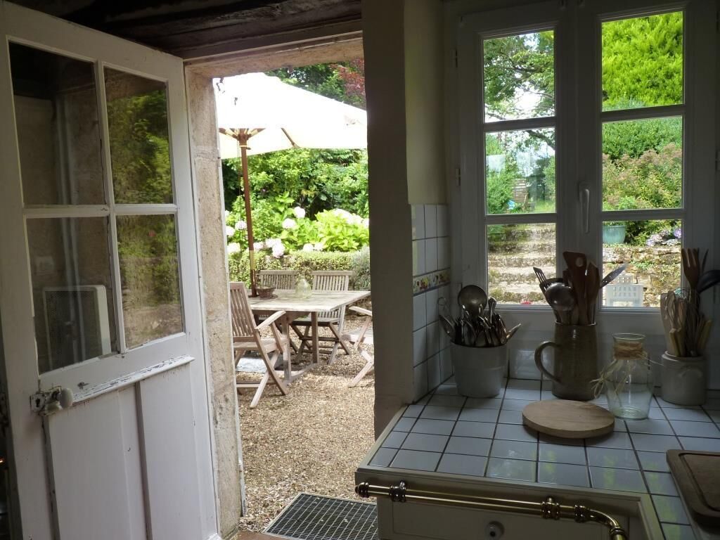 Een keuken met uitzicht op een tuin, een eethoek met tuinmeubilair en een betegelde spatwand.