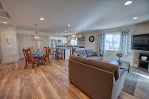 Relax in this inviting living space with a large sofa, dining table, and mounted TV.