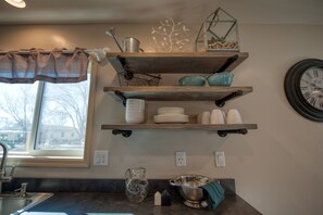 Kitchen area with a view of the neighborhood, featuring a sink, pitcher, and kitchenware on display.