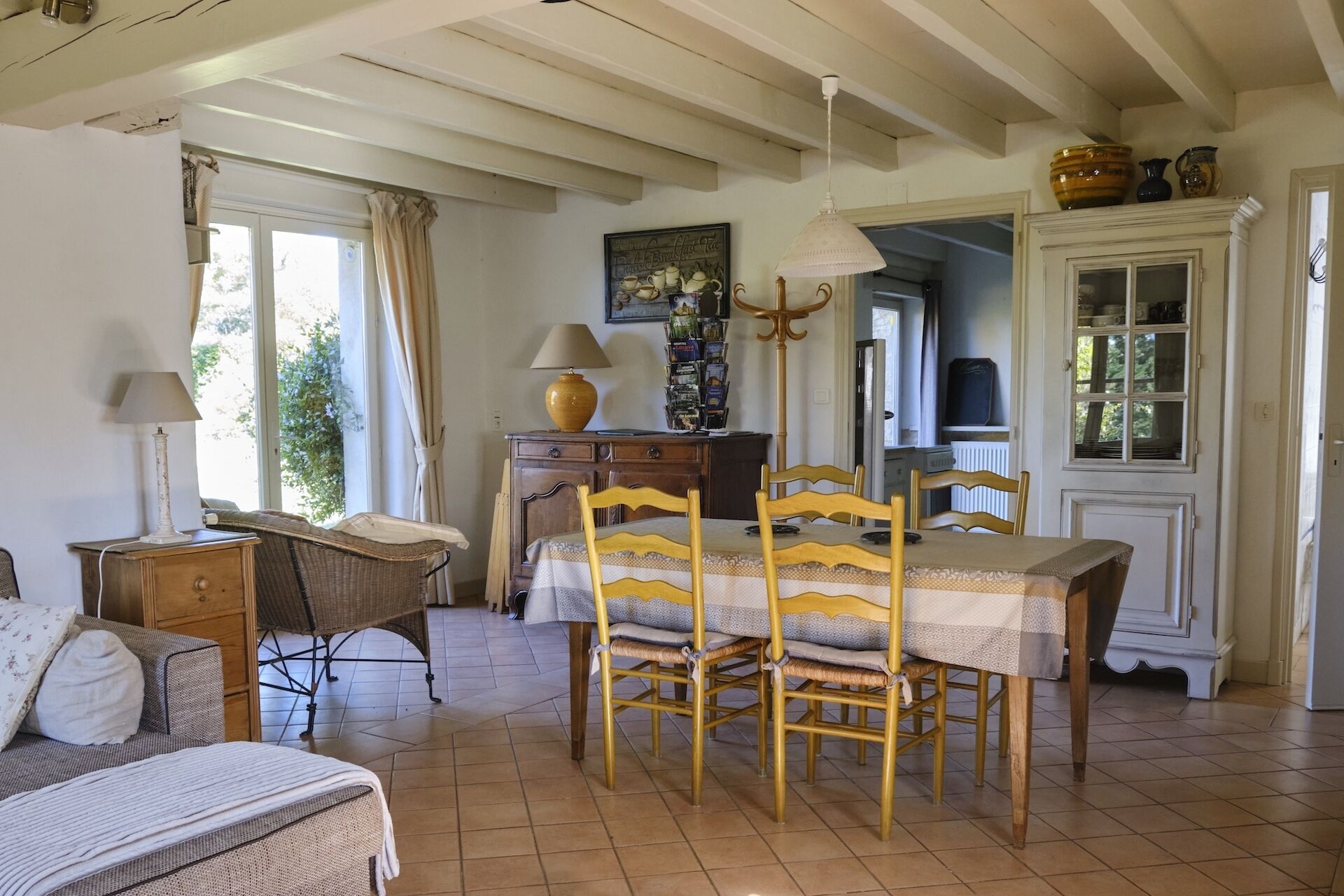 Un coin repas accueillant avec une table et des chaises en bois, une lampe et un buffet contenant de la vaisselle.