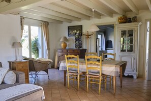 A cozy dining area with a wooden table and chairs, a lamp, and a cabinet with dishes.