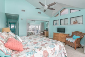 A bedroom with a bed, a television, a wicker chair, and a ceiling fan. - Sun, Beach, Pool & Pickle Ball - Relax & Enjoy Gulf Shores @ Ocean's Spell (Gulf Shores)
