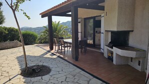 Un patio con piso de piedra, una pérgola, una parrilla y vistas al paisaje.