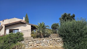 Una casa con pared de piedra, balcón y cielo azul despejado.