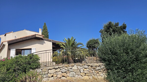 A house with a stone wall, a balcony, and a clear blue sky. - 900m from beach and stores, air-conditioned villa, swimming pool. Sea and harbor view (Cavalaire-Sur-Mer)