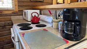 A kitchen with a stove, a red kettle, a coffee maker, and a microwave. - Relax In Southern Utah's Color Country! (MOUNT CARMEL)