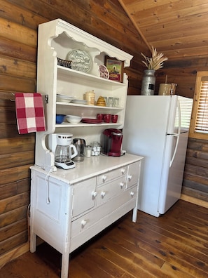 A kitchen with wooden walls, a white refrigerator, a white stove, and various kitchen items on shelves.