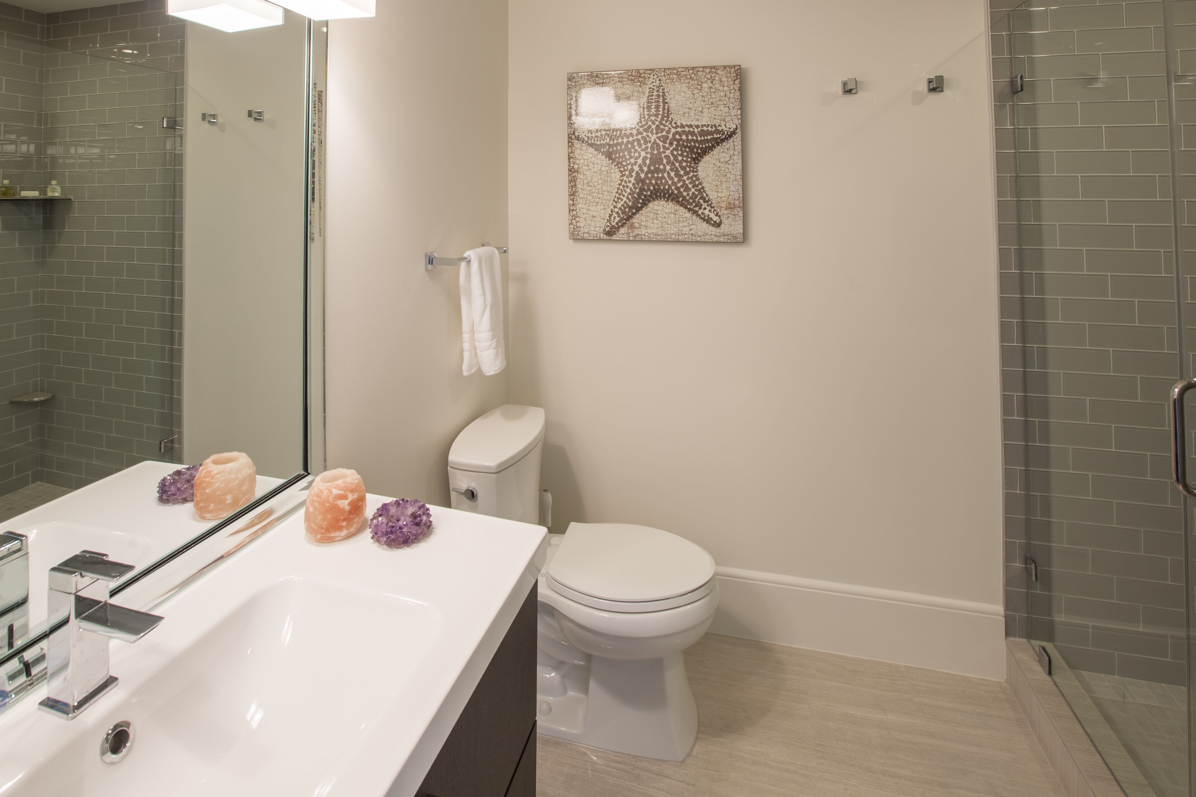 Une salle de bain avec un lavabo blanc, des toilettes et une cabine de douche en verre.
