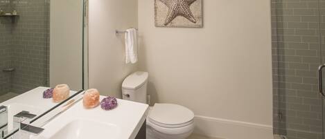 Une salle de bain avec un lavabo blanc, des toilettes et une cabine de douche en verre.