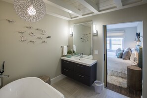 Ein modernes Badezimmer mit freistehender Badewanne, einem großen Spiegel und dekorativen Wandbildern.
