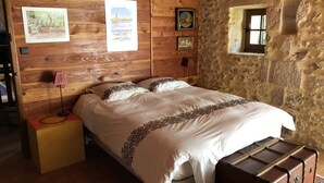 A wooden-paneled bedroom with a bed, a nightstand, a lamp, and a suitcase. - Beautiful house of 315 m² in a 4000 m² park with swimming pool 3 minutes from Périgueux (Champcevinel)