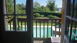 A view from a window with a wooden railing overlooking a swimming pool and a garden. - Beautiful house of 315 m² in a 4000 m² park with swimming pool 3 minutes from Périgueux (Champcevinel)