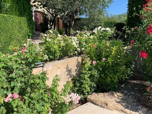Stroll through the beautifully maintained garden, featuring a variety of flowering plants and a tranquil pathway leading to the entrance.