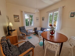 A cozy living room with a sofa, a dining table, and patterned chairs.