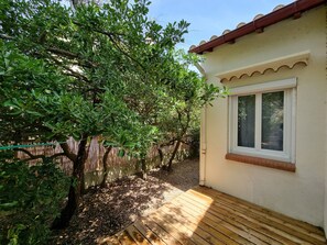 A wooden deck with a white window and a beige wall.