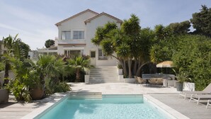 Un espace piscine offrant une vue dégagée sur la piscine, une terrasse en bois et un bâtiment à deux étages doté d’un balcon.