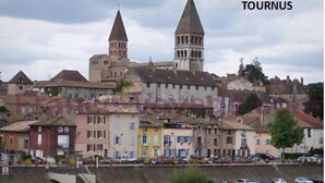 Un pueblo histórico con dos torres destacadas, edificios coloridos y un puerto deportivo con barcos.