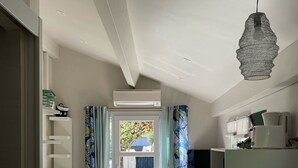 A modern bedroom with a bed, built-in shelving, and a view through a glass door to a garden. - holiday apartment seaside comfort air-conditioned  (Hyères)