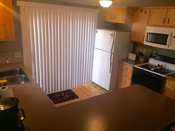A compact kitchen with a refrigerator, microwave, stove, and sink.