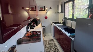 Una cocina moderna con armarios blancos, electrodomésticos de acero inoxidable y un ventanal con vistas al verdor.