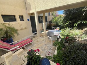 A patio area with a lounge chair, a table with a grill, and various potted plants. - Air-conditioned apartment with sea view 50m from the sea in Sant Ambroggio (Lumio)