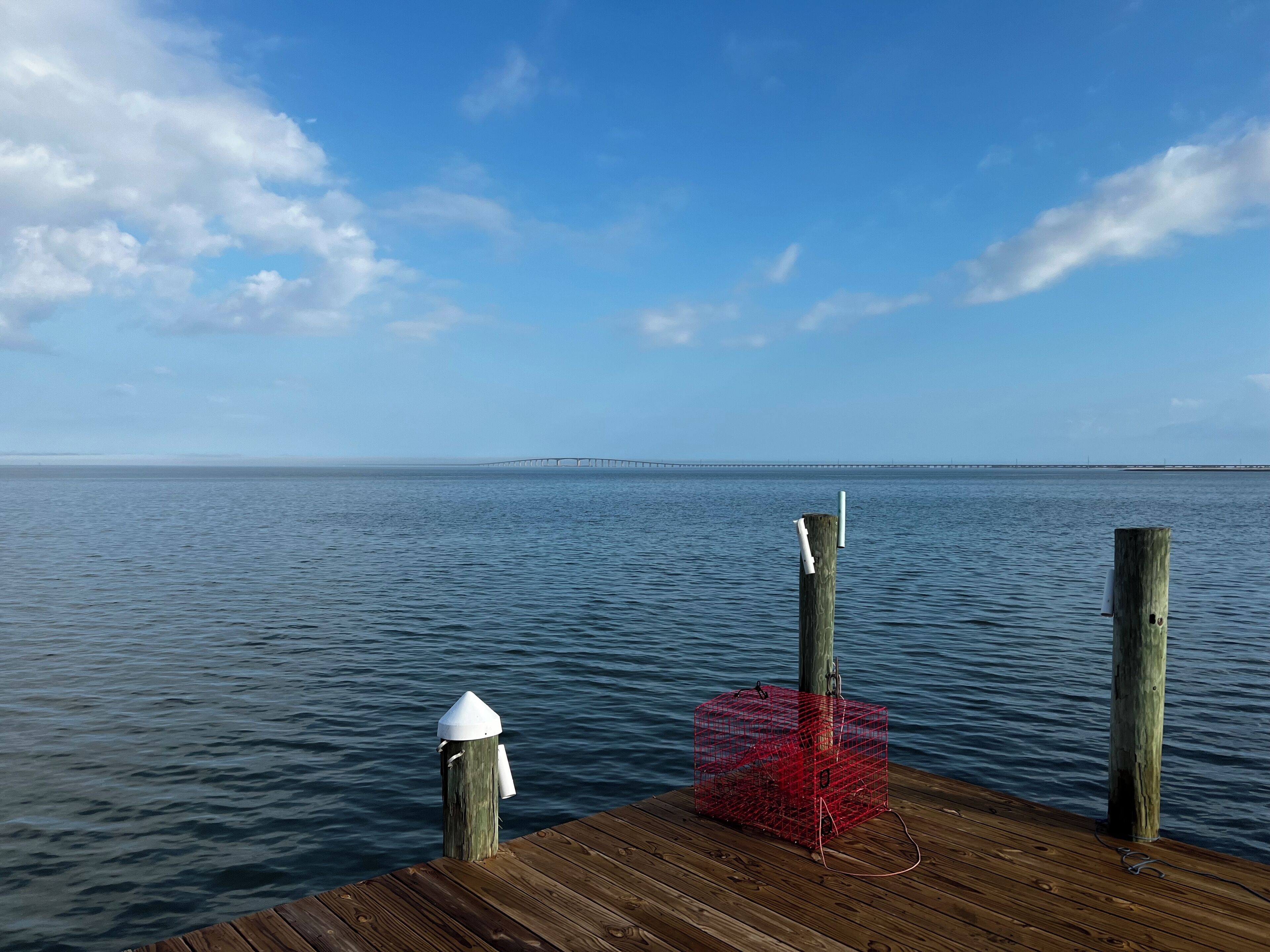 A wooden dock extending into calm waters with a clear sky.