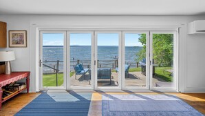 A room with a large sliding glass door leading to a deck with outdoor seating and a grill.