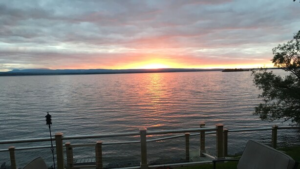 A sunset view from a deck with outdoor seating and a fire pit.