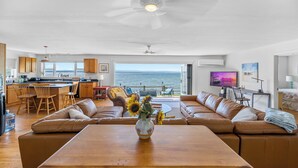A spacious living area with a large sofa, a wooden coffee table, and a view of the ocean.