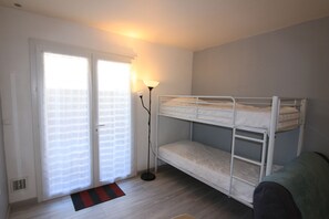 Une chambre avec un lit superposé, une lampe sur pied, une porte coulissante et un petit tapis.