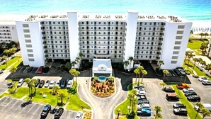 Un hotel a più piani con un cortile centrale, area parcheggio e vista sull'oceano.