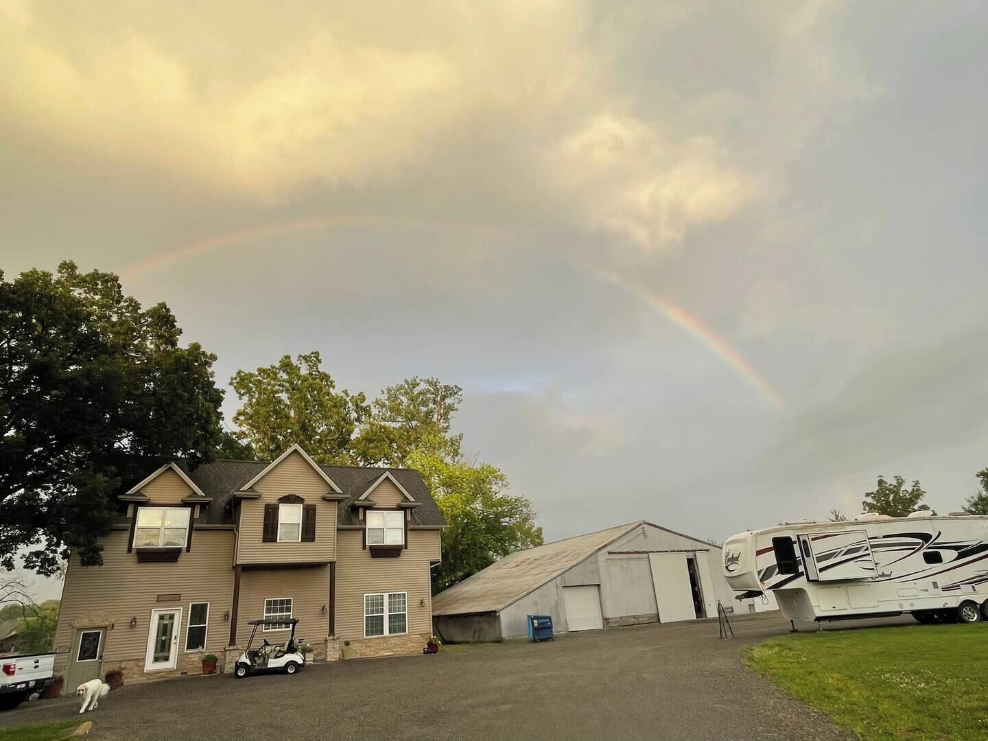 A two-story house with a garage and a large RV parked in front.