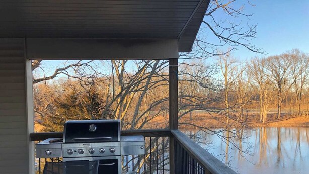 A covered outdoor grill area with a view of a lake and trees. - 3 Bedroom, full kitchen and remodeled bathroom. Water-views from the Kitchen and covered deck. (Caseyville)