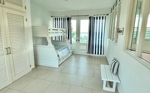 Un dormitorio con una cama litera, un banco y vistas al exterior.