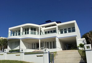 Un bâtiment moderne à deux étages, doté d’une façade incurvée, de balcons et d’un espace extérieur couvert.