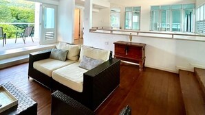 A spacious living area with a high ceiling and wooden beams, a sofa, a dining table, and a view of greenery outside. - OCEAN VIEW VILLA WITH PRIVATE POOL ,STEPS FROM SECLUDED BEACH, GATED COMMUNITY! (Yabucoa)