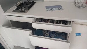 Una cocina con estufa a gas, varios cajones y zona de fregadero con vajilla.