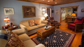 A cozy living room with a wooden ceiling, a sofa, a coffee table, and a patterned rug. - Charming Cannon Beach Cottage- Perfect Family Getaway near the beach! (Cannon Beach)