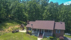 A two-story house with a brick exterior, a front porch, and a satellite dish. - Old Wagon Lodge | Spacious Retreat | WiFi & Hot Tub + Theater Room (Luray)
